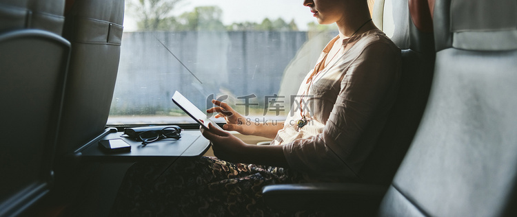 坐火车旅行的女人坐在窗边用手机