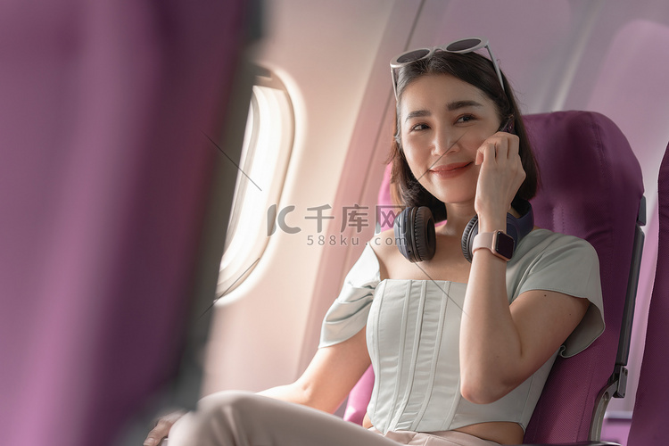 快乐的亚洲女性坐在飞机上，在旅