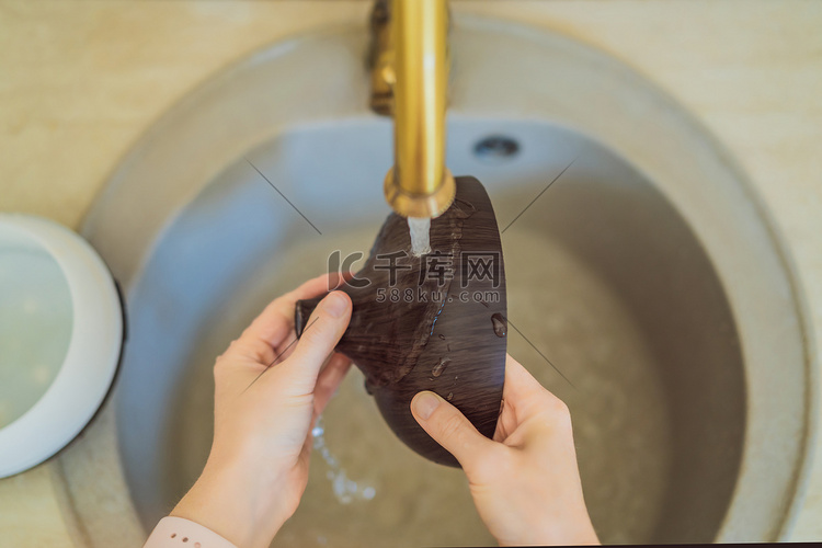 女人在水龙头里洗香薰机。