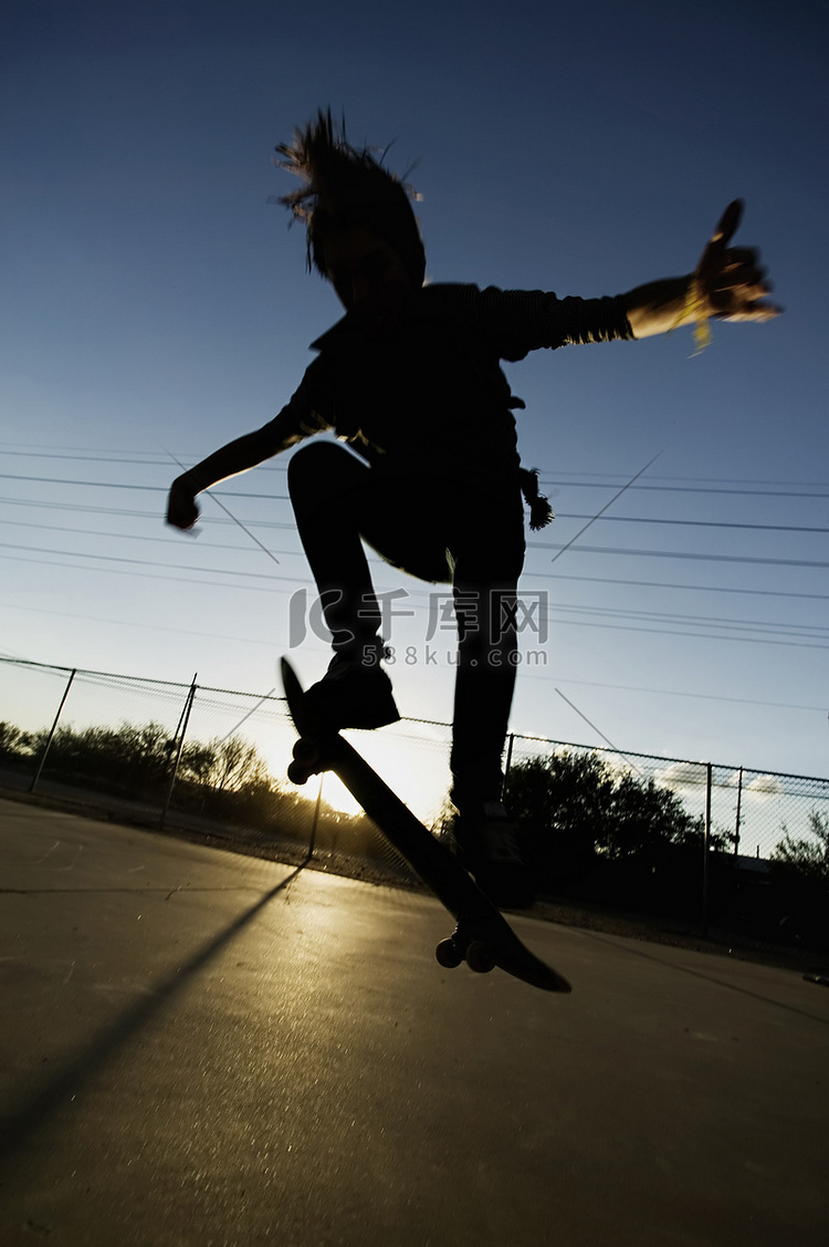 日落时的少年滑板运动员