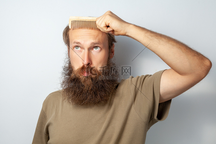 成年秃头男性拿着梳子，患有脱发