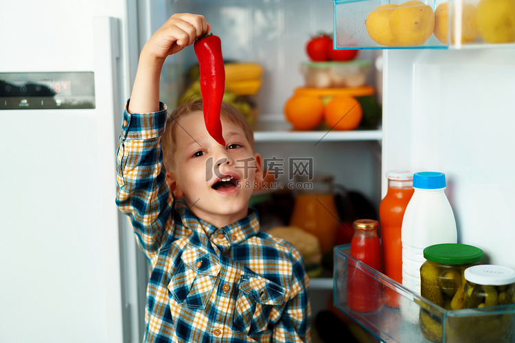 小男孩站在打开的冰箱前选择食物