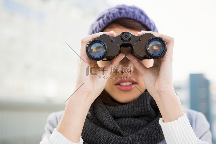 穿着冬装的女人看着双筒望远镜