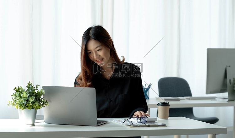 迷人的亚洲女商人坐在办公室的笔