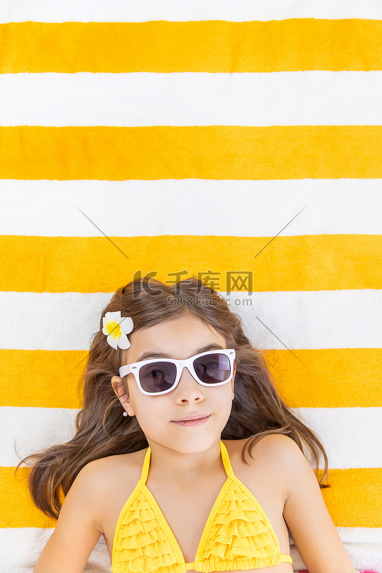小女孩在海边的沙滩巾上。