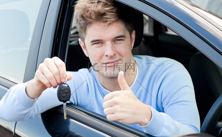 积极的年轻人拿着钥匙坐在车里