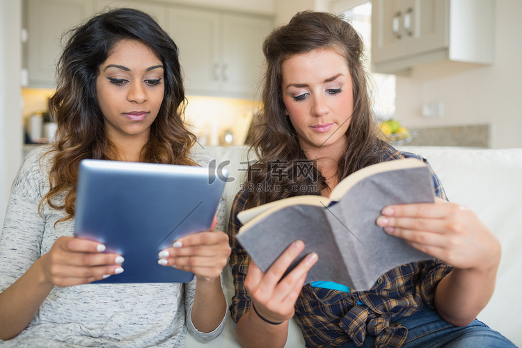 女孩读一本书，拿着平板电脑