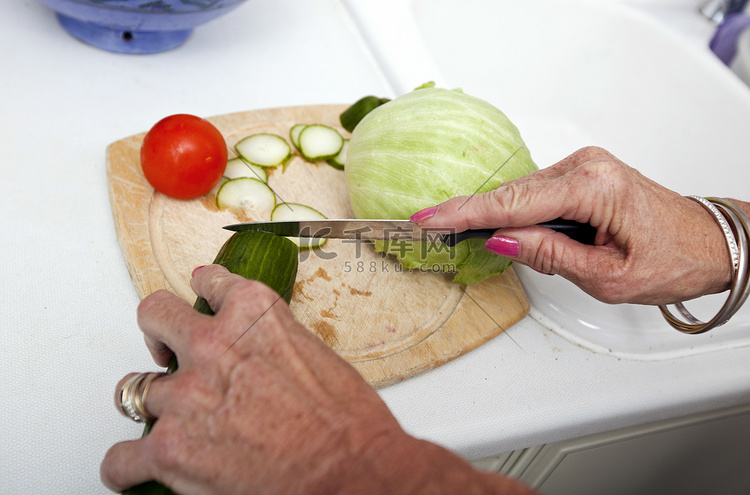 高级妇女在厨房切板上切菜的裁剪