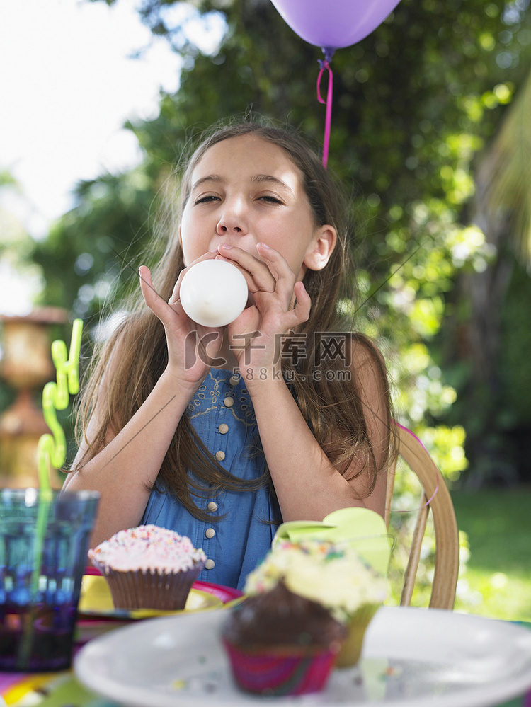 小女孩在户外生日聚会上吹气球
