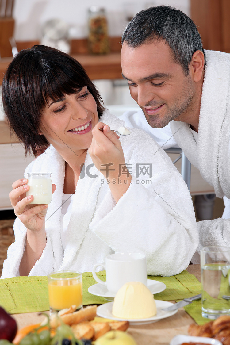一位女士在早餐时给丈夫一茶匙酸