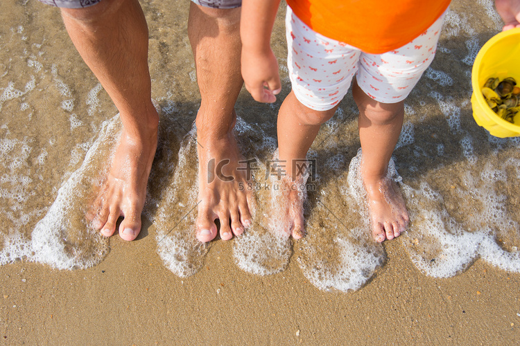 两双腿成人和儿童被海浪冲刷