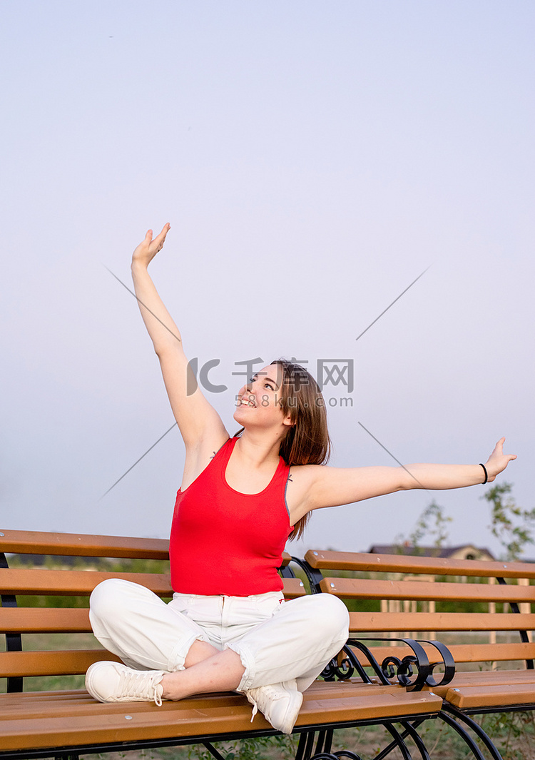 快乐的年轻女人盘腿坐在长凳上