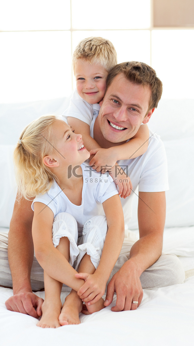 有爱心的父亲和他的孩子们坐在床