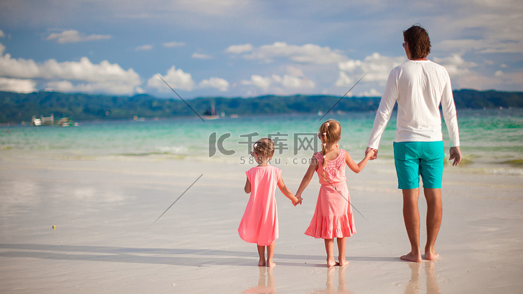 热带白色海滩上两个小女孩和年轻