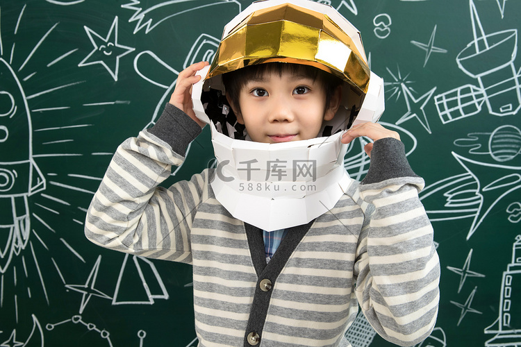 戴着航天员头盔的小男孩站在黑板