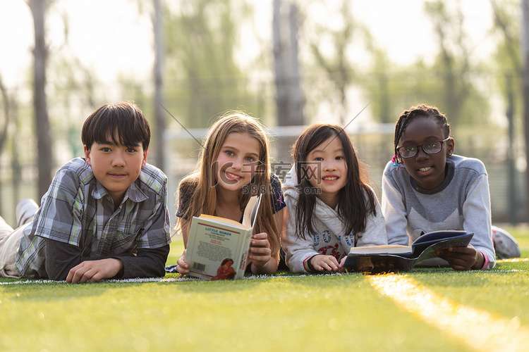 可爱的小学生们趴在草地上看书