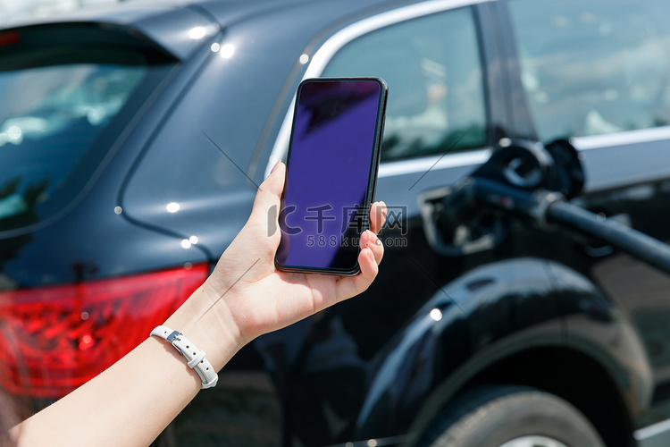 青年女人使用手机自助充电汽车