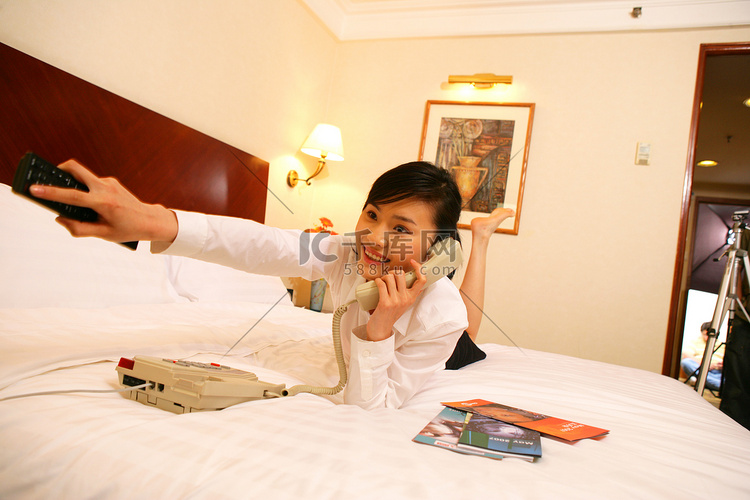 年轻女士在酒店床上愉快地打电话