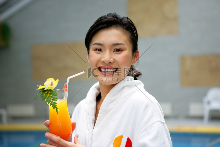 年轻女士在酒店游泳池边手拿果汁