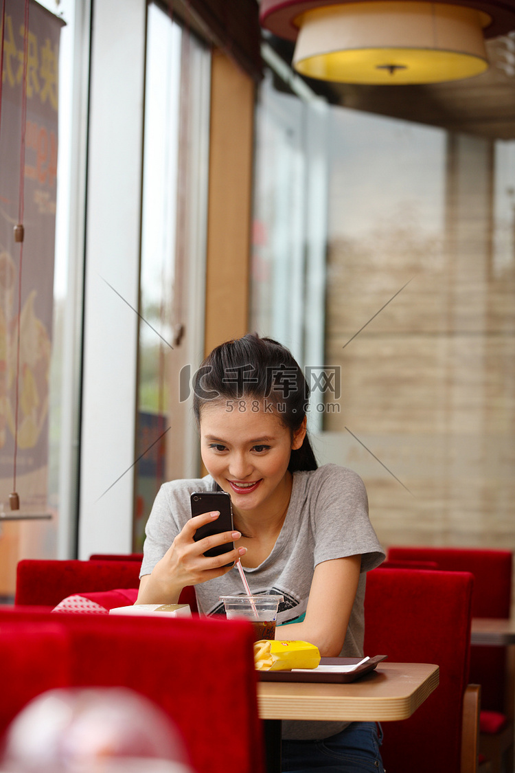青年女人餐厅里看手机