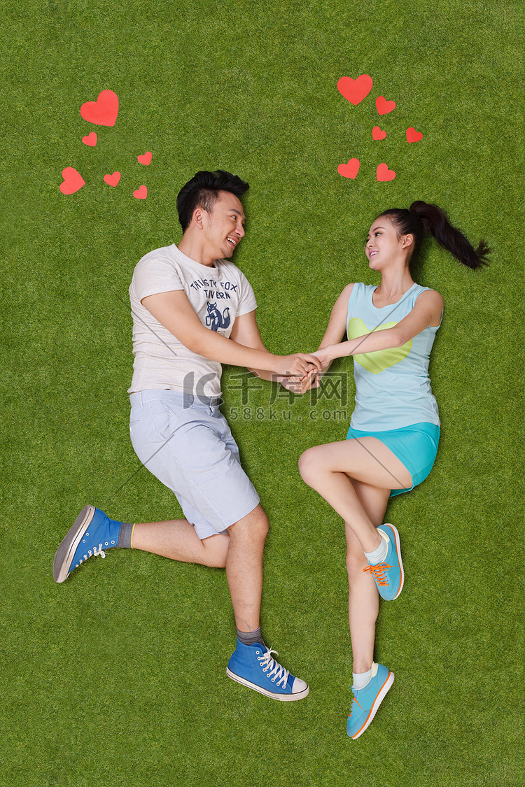 年轻男女手牵手躺在草地上