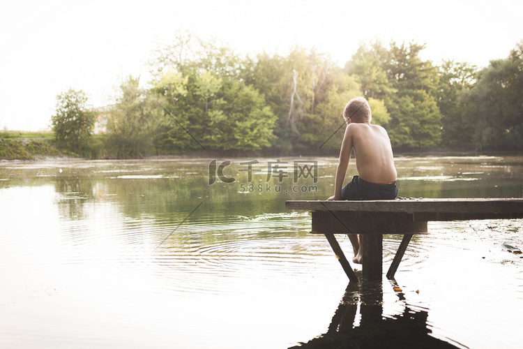 孤独的男孩坐在湖边