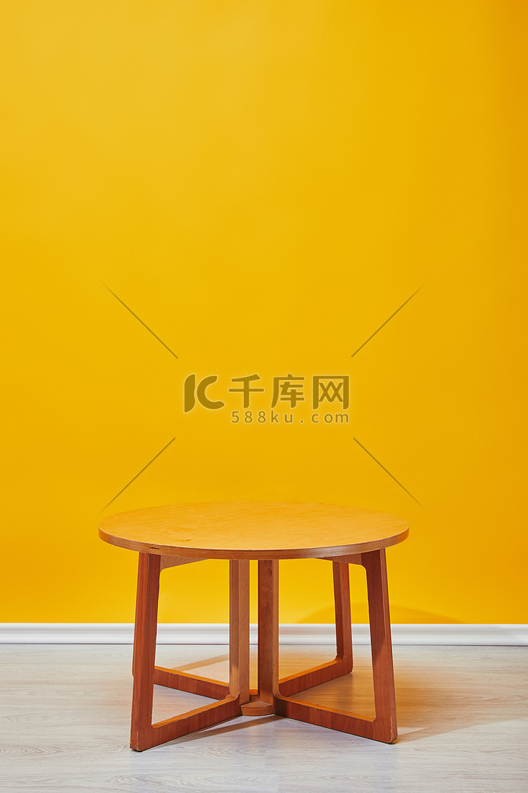 背景为黄色墙壁的小木咖啡桌 