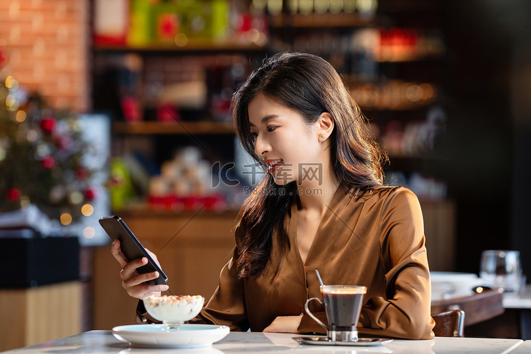 咖啡馆内边喝咖啡边使用手机的青