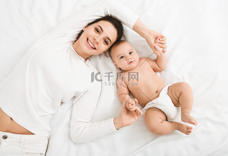 快乐的母亲和婴儿躺在床上的顶视
