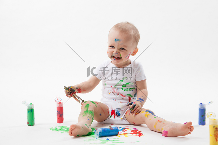 可爱的小婴儿绘画与画笔和彩色颜