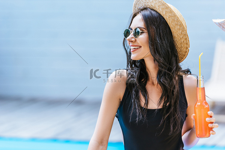 微笑的年轻妇女在泳装举行瓶与清
