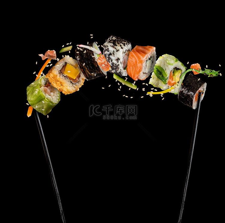 寿司放在黑色背景上的筷子之间