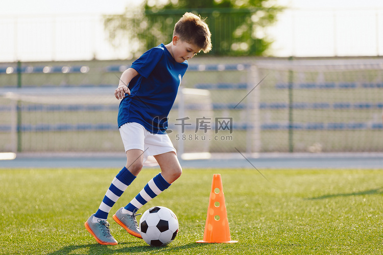 穿着足球制服的男孩用球练习。孩