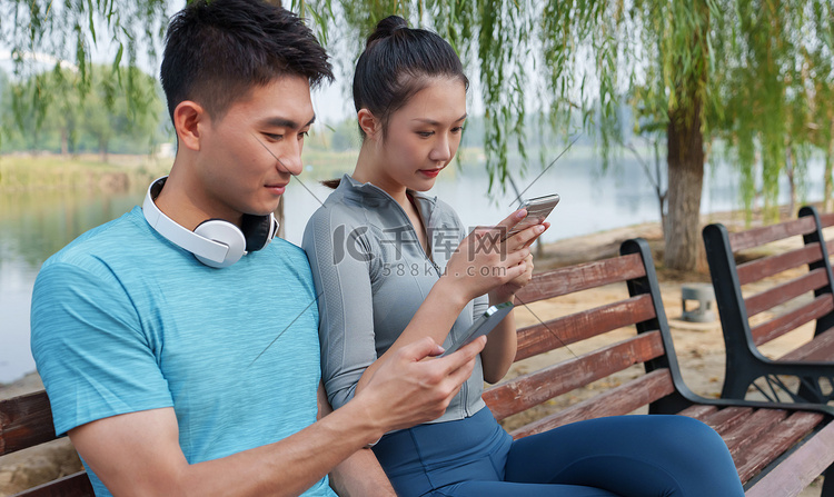 青年情侣坐在户外看手机