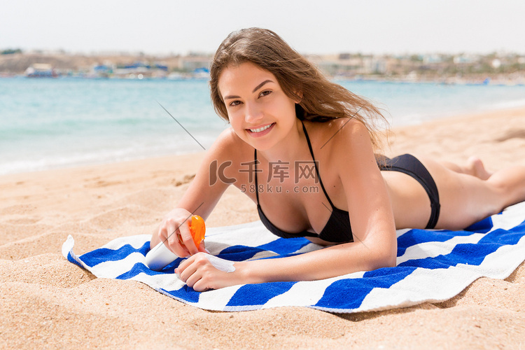 年轻快乐的女人躺在靠近大海的毛
