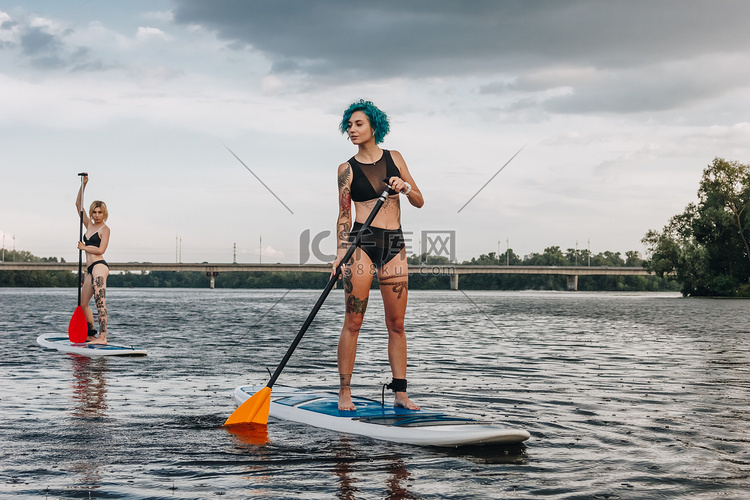 运动妇女在河上 paddleboarding 站立