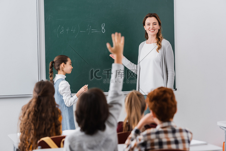 微笑的老师看着学生举手表决模糊