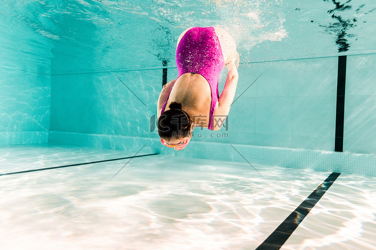 在游泳池水下潜水的粉红色泳衣妇