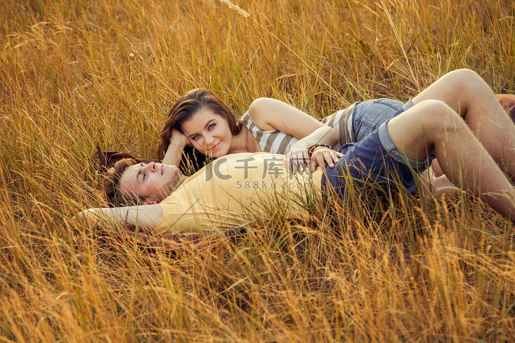 爱的情侣躺在秋季公园的花卉领域