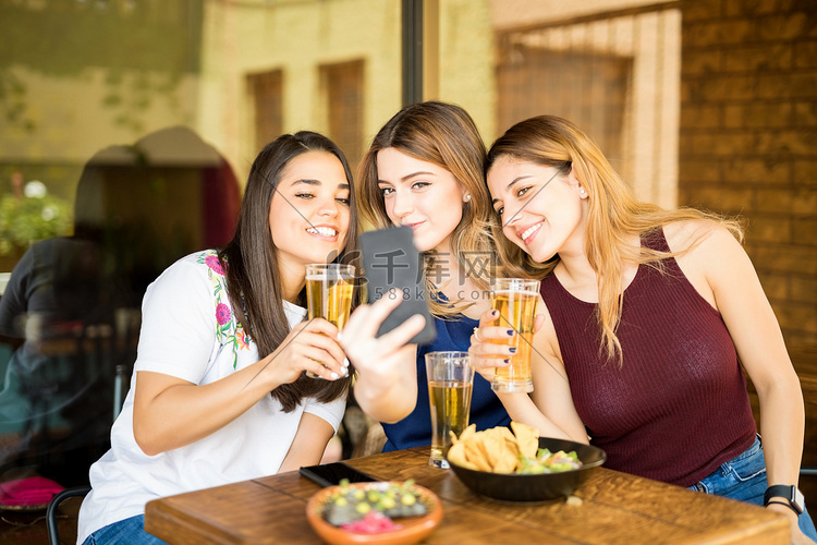 三名年轻女性坐在餐馆里喝啤酒,