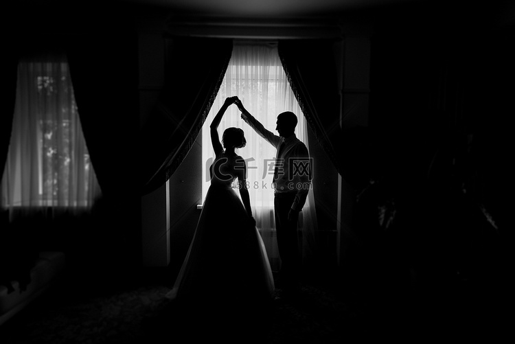 新娘和新郎的剪影在窗口。新娘和
