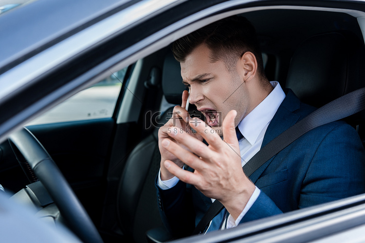 愤怒的商人在汽车上用智能手机谈