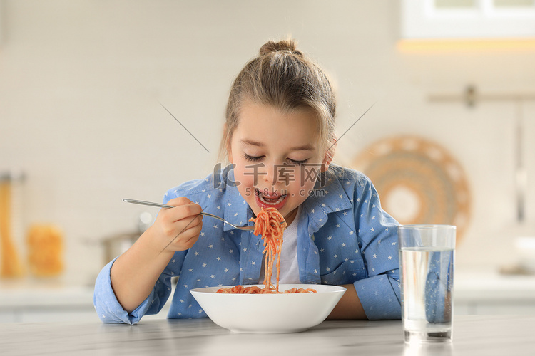 可爱的小女孩在厨房的饭桌上吃着