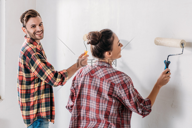 幸福的年轻夫妇在格子衬衫油漆墙