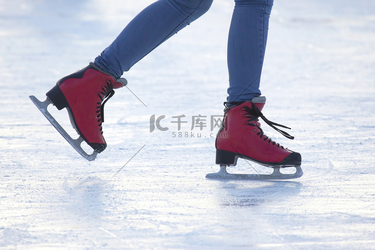 脚踏在溜冰场上的红色冰鞋。业余