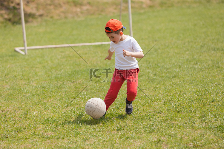 小男孩在公园踢球。在公园踢足球