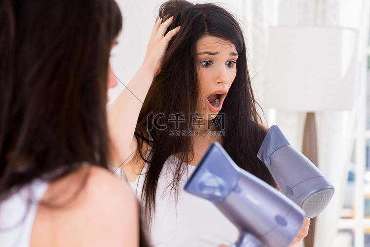 震惊的女人看着干燥的头发