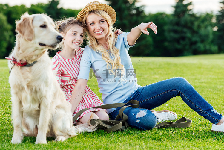母亲和女儿带着狗在公园里