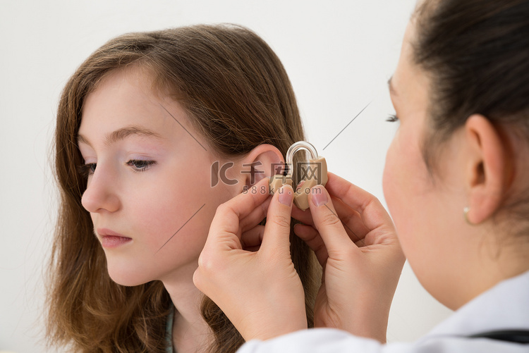 医生在女孩的耳边插入助听器