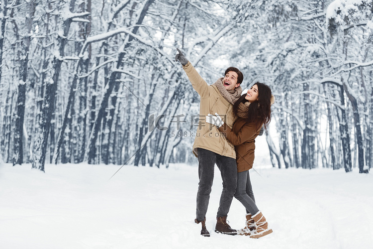 快乐的男人展示他女朋友站在雪地